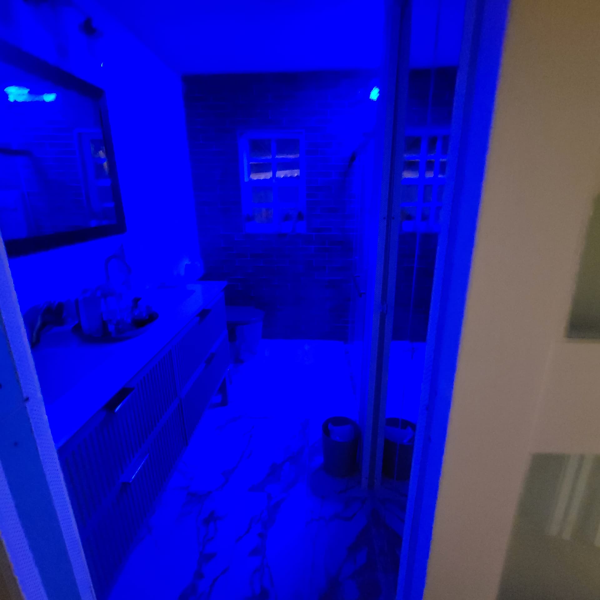 Completed modern bathroom viewed through the doorway showing double vanity, dark subway tile back wall and glass shower