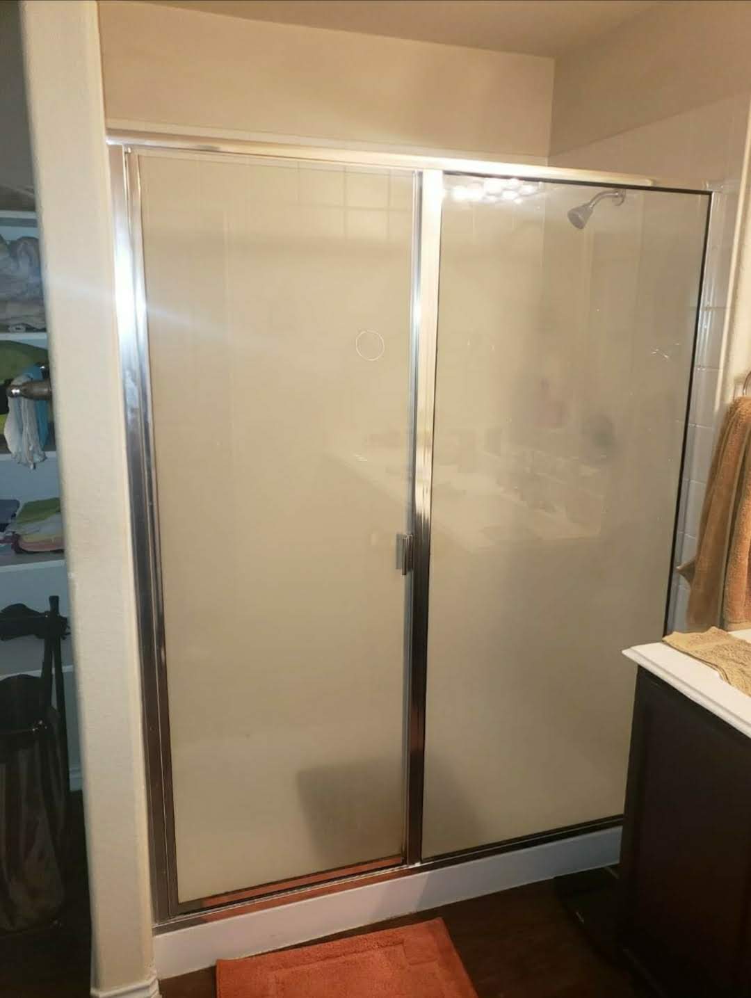Dated framed shower enclosure with frosted glass doors before remodeling
