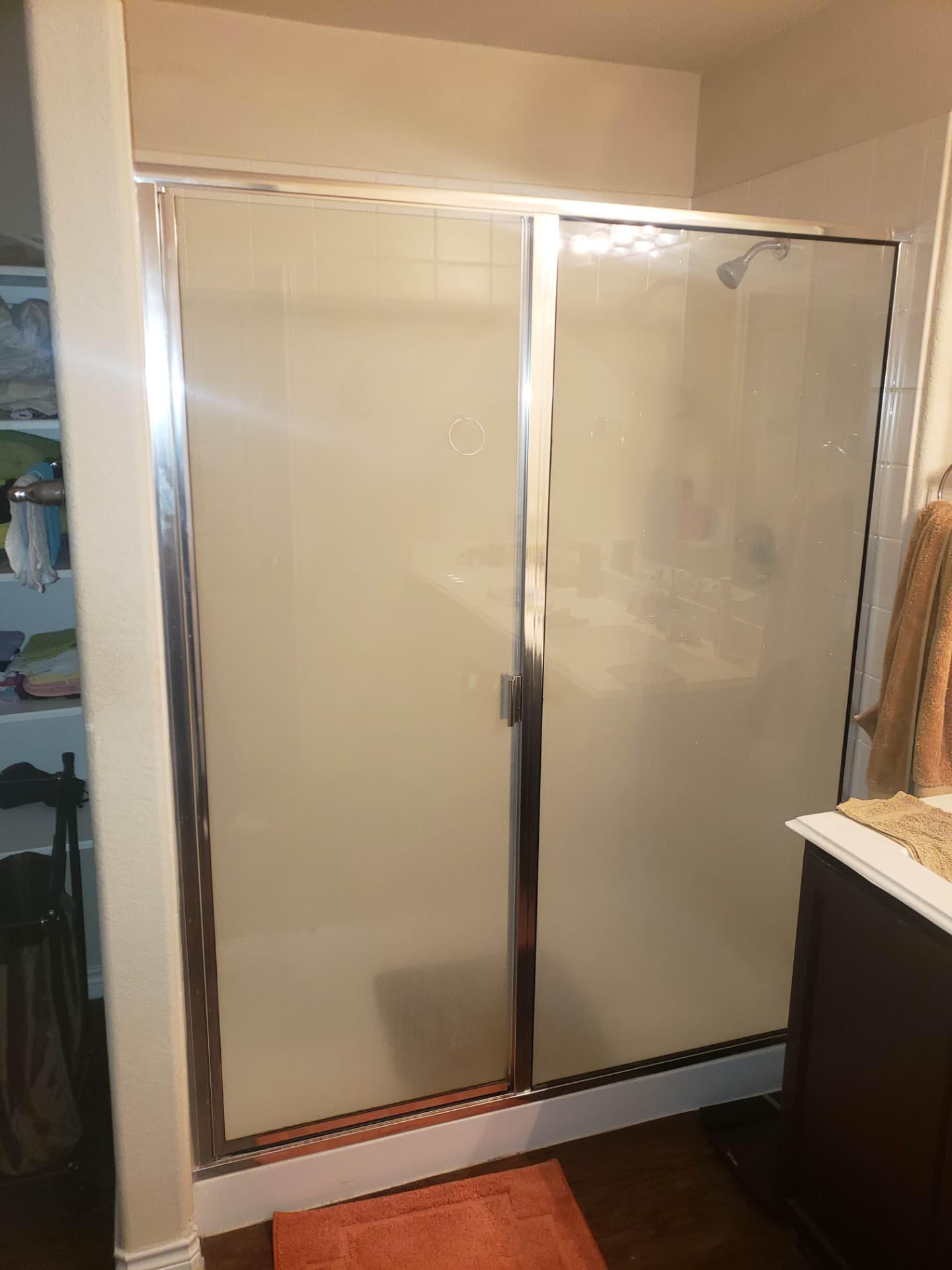 Original chrome-framed shower door and dated tile before conversion