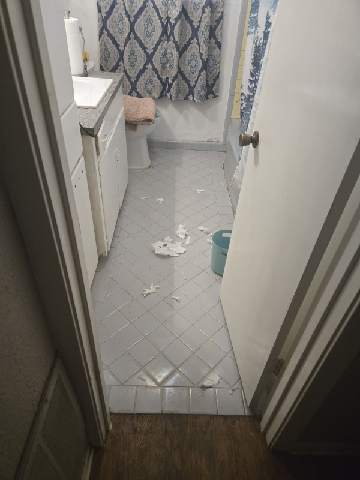 Diagonal light grey floor tile being installed in a bathroom with vanity and toilet in place