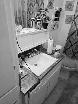 Original cluttered bathroom vanity and drop-in sink before remodeling